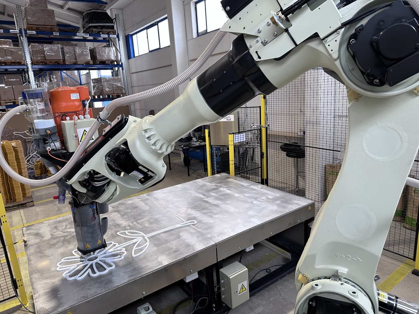 Velkoplošný 3D tisk světelné dekorace pomocí robotického ramene v dílně.